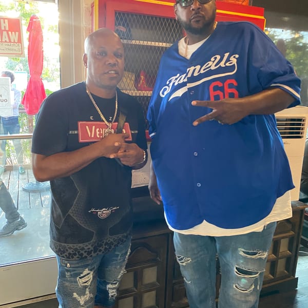 Two men posing for a photo inside Frank's Famous Chicken & Waffles restaurant.