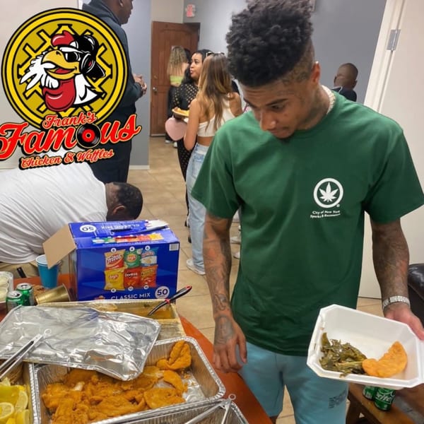 A man in a green shirt holds a plate of Frank's Famous chicken and collard greens at a buffet.