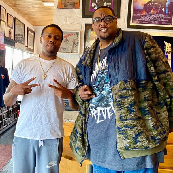 Two men posing with peace signs inside Frank's Famous Chicken & Waffles restaurant.