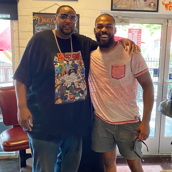 Two men, one in a "Westside" shirt, smiling with arms around each other at Frank's Famous.