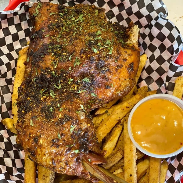 Frank's Famous Chicken & Waffles' crispy fried chicken with fries and dipping sauce in a basket.