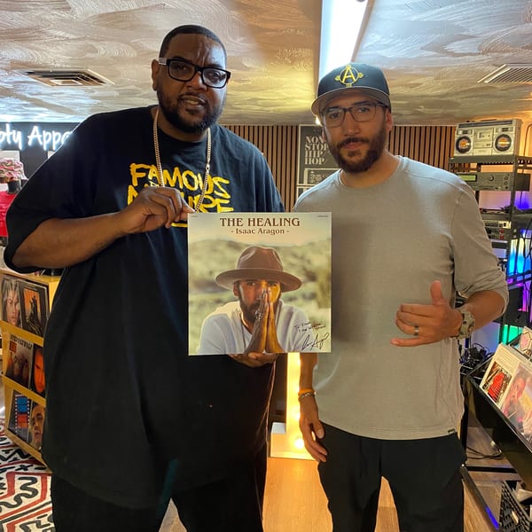Two men, one in a Frank's Famous shirt, holding up a signed vinyl record album.